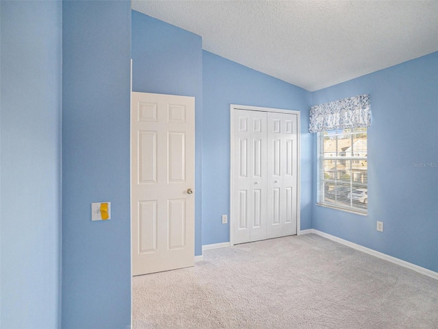 unfurnished bedroom with a textured ceiling, light carpet, a closet, and vaulted ceiling