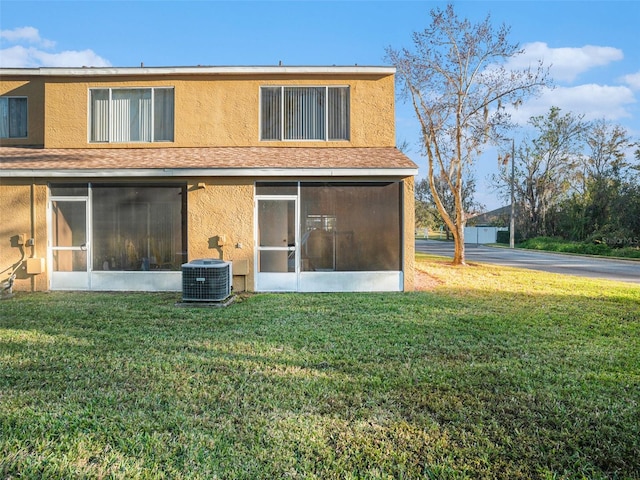 rear view of property featuring a sunroom, central air condition unit, and a lawn