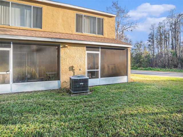 back of house featuring a lawn, central AC, and a sunroom