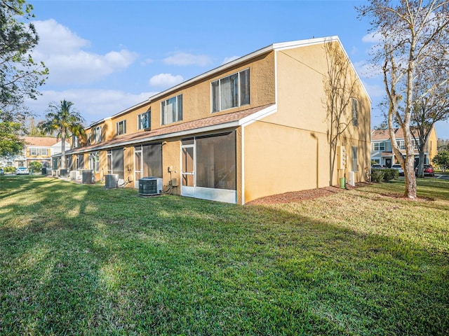 rear view of property featuring a sunroom, central AC unit, and a lawn