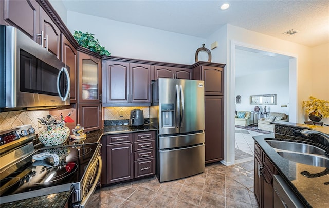 kitchen featuring stainless steel appliances, sink, decorative backsplash, and dark stone counters