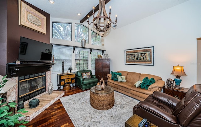 living room featuring a notable chandelier, a stone fireplace, high vaulted ceiling, and hardwood / wood-style flooring