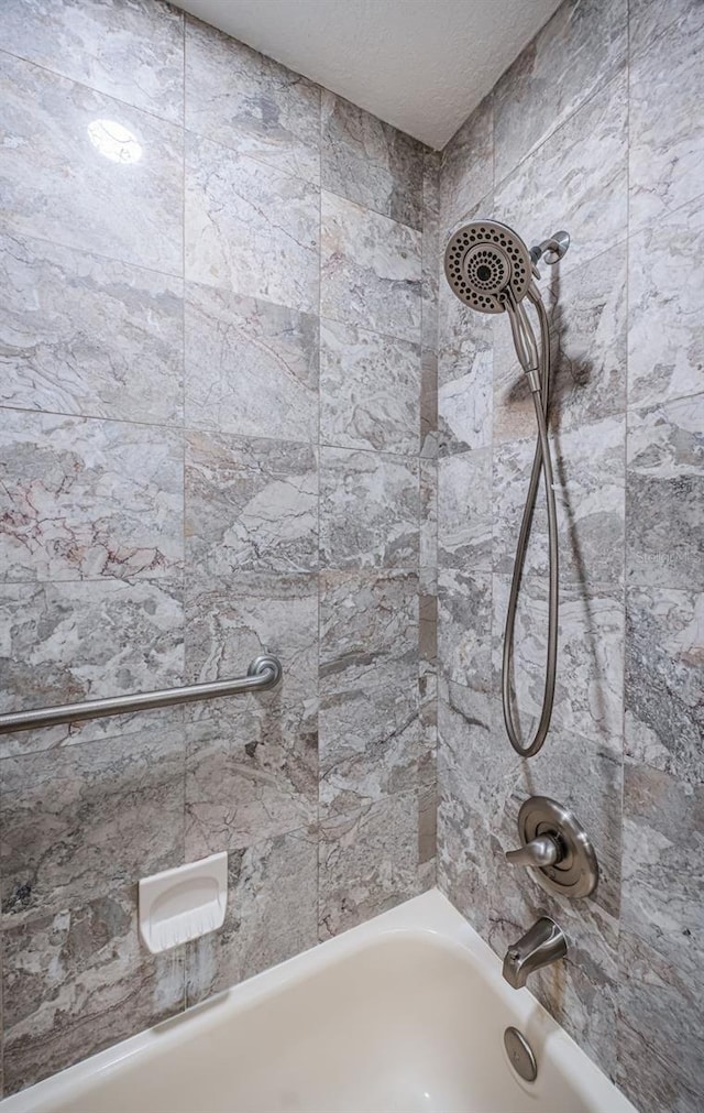 bathroom featuring tiled shower / bath combo and a textured ceiling