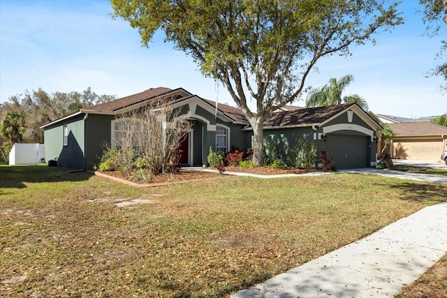 view of front of property with a garage, driveway, a front yard, and stucco siding