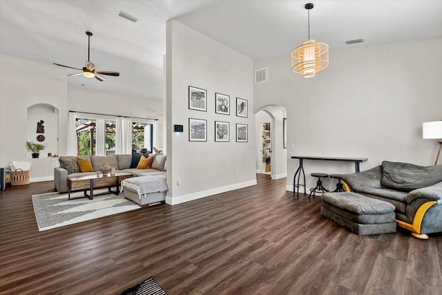 living area featuring arched walkways, dark wood-style floors, visible vents, and baseboards