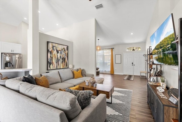 living room with high vaulted ceiling, wood finished floors, visible vents, and recessed lighting