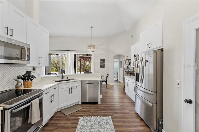 kitchen with appliances with stainless steel finishes, arched walkways, white cabinets, and a sink