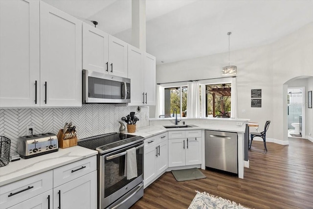 kitchen featuring arched walkways, white cabinets, dark wood-type flooring, stainless steel appliances, and a sink