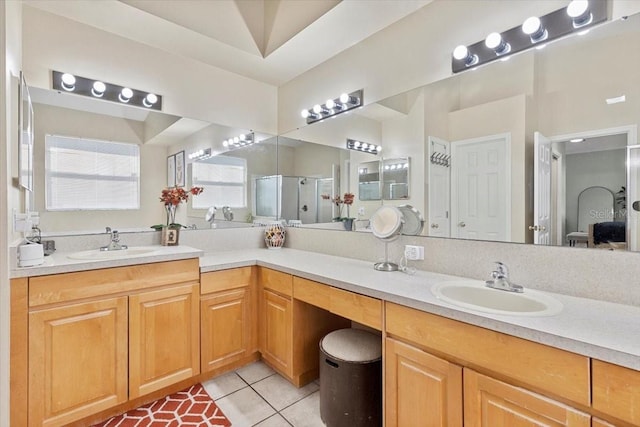 full bath with a stall shower, double vanity, a sink, and tile patterned floors