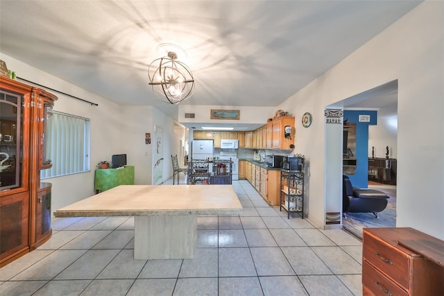 kitchen with hanging light fixtures, a notable chandelier, white appliances, a breakfast bar area, and light tile patterned floors