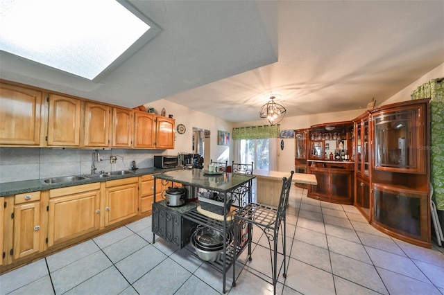 kitchen featuring backsplash, a skylight, sink, and light tile patterned floors