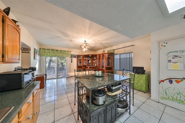 kitchen featuring a skylight, a textured ceiling, sink, light tile patterned floors, and a kitchen island