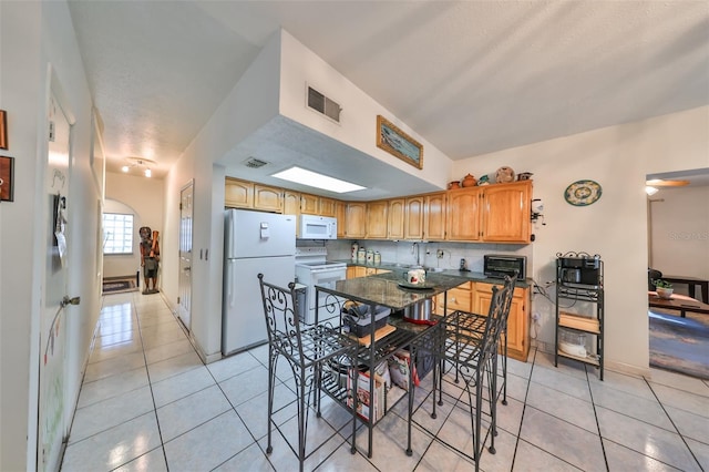 kitchen with white appliances, backsplash, and light tile patterned flooring