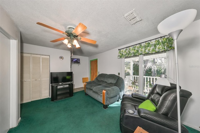 carpeted living room featuring ceiling fan and a textured ceiling