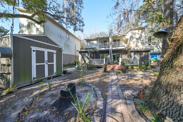 rear view of property featuring a balcony and a shed