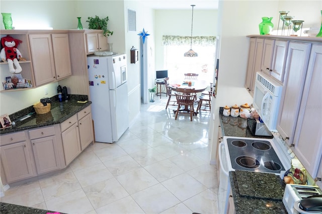 kitchen featuring dark stone countertops, hanging light fixtures, and white appliances