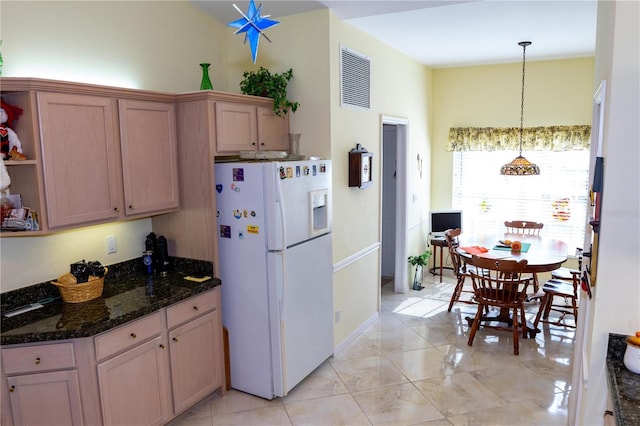 kitchen with dark stone counters, light brown cabinetry, hanging light fixtures, and white fridge with ice dispenser