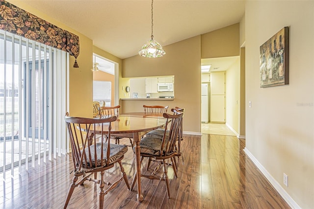 dining space with hardwood / wood-style flooring, ceiling fan, and lofted ceiling