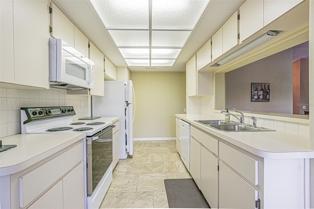 kitchen featuring kitchen peninsula, tasteful backsplash, white appliances, sink, and white cabinets