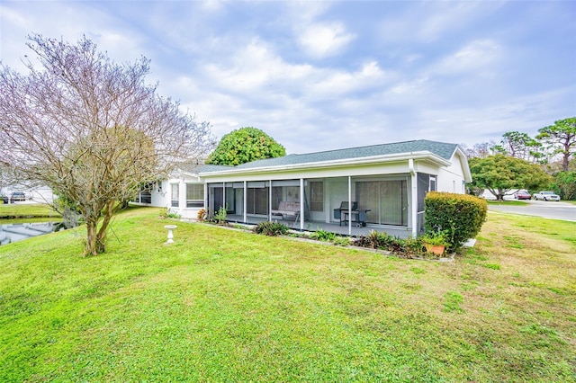 back of house featuring a sunroom and a lawn