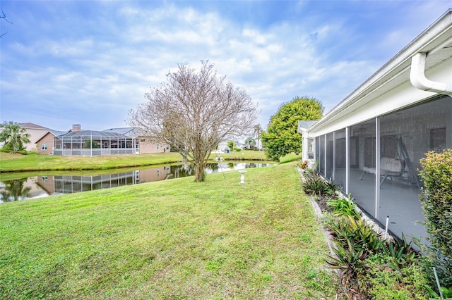 view of yard with a sunroom and a water view