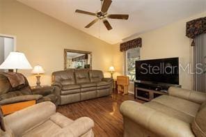 living room featuring dark hardwood / wood-style flooring, vaulted ceiling, and ceiling fan