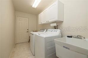 laundry area with washer and clothes dryer, cabinets, and sink