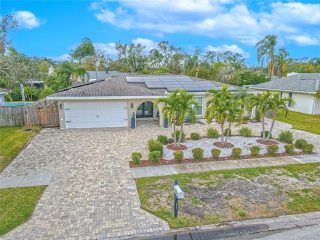 single story home featuring solar panels and a garage