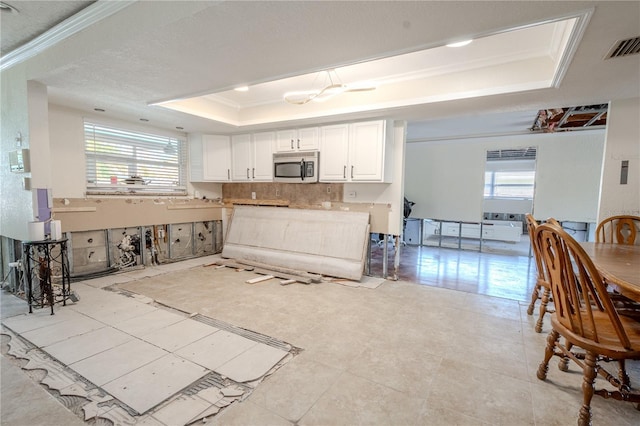 kitchen with a tray ceiling, crown molding, plenty of natural light, and white cabinets