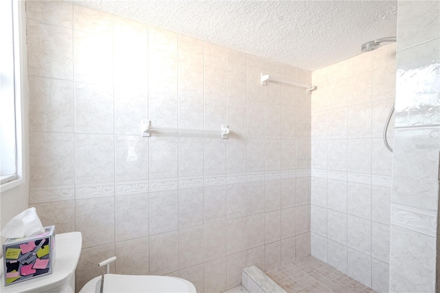 bathroom with a tile shower, a textured ceiling, and toilet