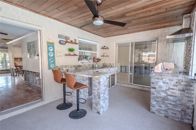 interior space with exterior kitchen, ceiling fan, and a bar