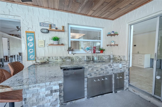 kitchen with kitchen peninsula, light stone countertops, sink, wooden ceiling, and fridge