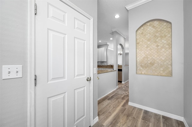 hall featuring a textured ceiling, crown molding, and hardwood / wood-style floors