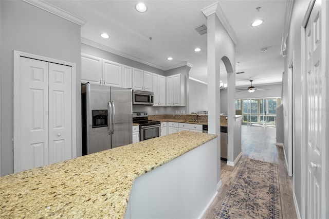 kitchen featuring light hardwood / wood-style flooring, white cabinets, appliances with stainless steel finishes, ceiling fan, and sink