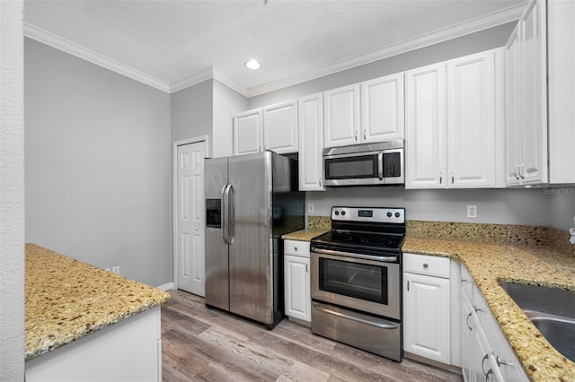 kitchen with appliances with stainless steel finishes, white cabinets, crown molding, and light stone countertops