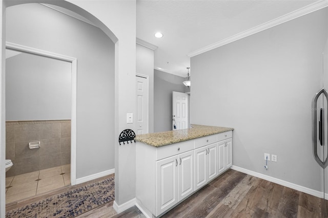 interior space featuring light stone countertops, white cabinetry, crown molding, and dark wood-type flooring