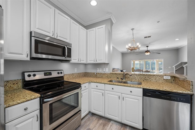 kitchen with kitchen peninsula, stainless steel appliances, ceiling fan with notable chandelier, white cabinets, and sink