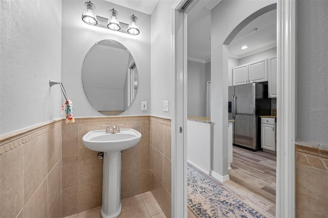 bathroom featuring ornamental molding, tile walls, and sink