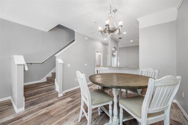 dining room with hardwood / wood-style flooring, an inviting chandelier, and crown molding