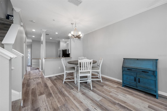 dining space with a chandelier, light hardwood / wood-style floors, and crown molding