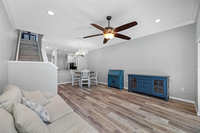 living room with ceiling fan with notable chandelier, hardwood / wood-style floors, and crown molding