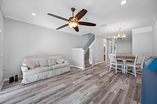 living room with ceiling fan with notable chandelier, crown molding, and hardwood / wood-style floors