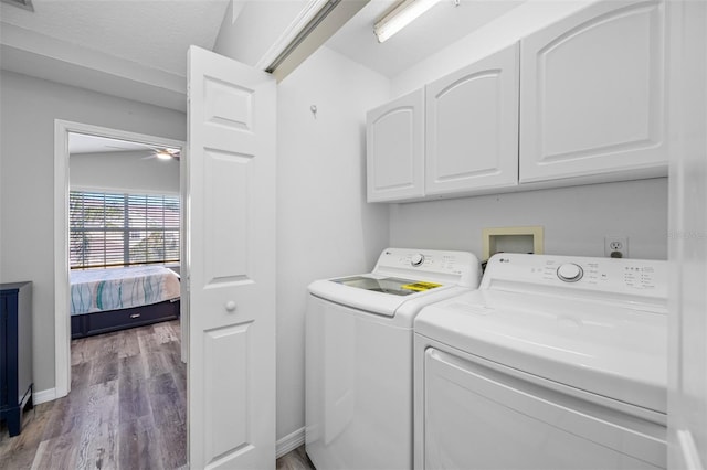 washroom featuring washing machine and dryer, hardwood / wood-style floors, and cabinets