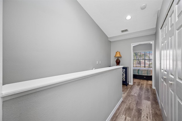 hallway with hardwood / wood-style floors and vaulted ceiling