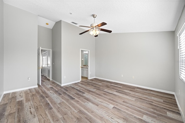 empty room featuring lofted ceiling, a textured ceiling, light wood-type flooring, and ceiling fan