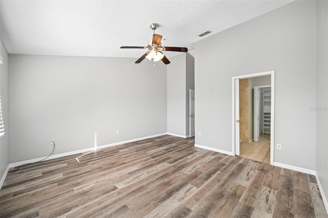 spare room with wood-type flooring, a textured ceiling, ceiling fan, and vaulted ceiling