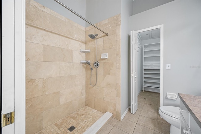 bathroom with a tile shower, toilet, vanity, and tile patterned flooring