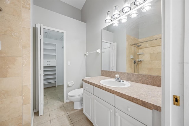 bathroom with tiled shower, tile patterned flooring, vanity, and toilet