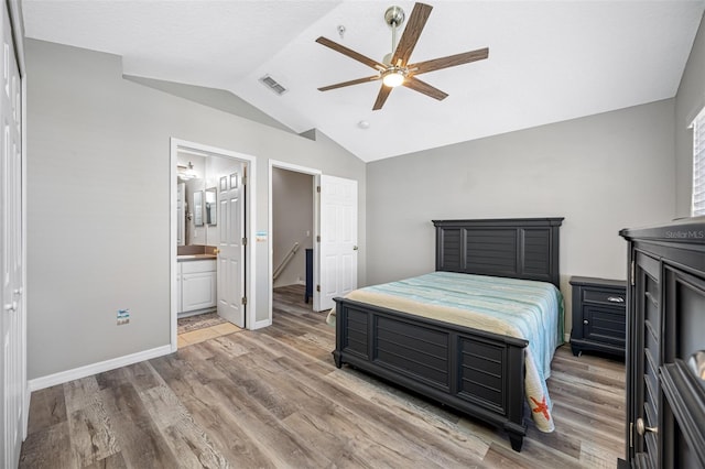 bedroom featuring vaulted ceiling, ensuite bath, ceiling fan, and wood-type flooring