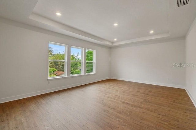 unfurnished room featuring wood-type flooring and a tray ceiling